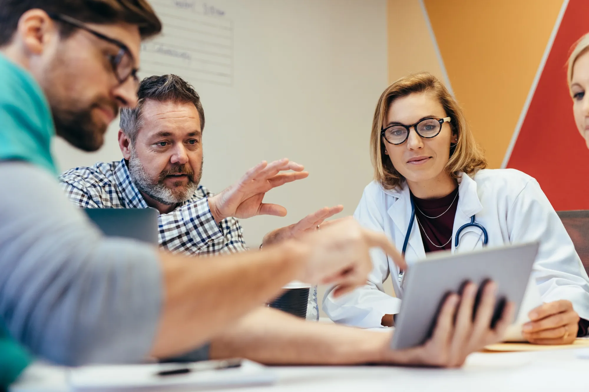 Gespräch zwischen Ärztin und drei Patienten an einem Tisch