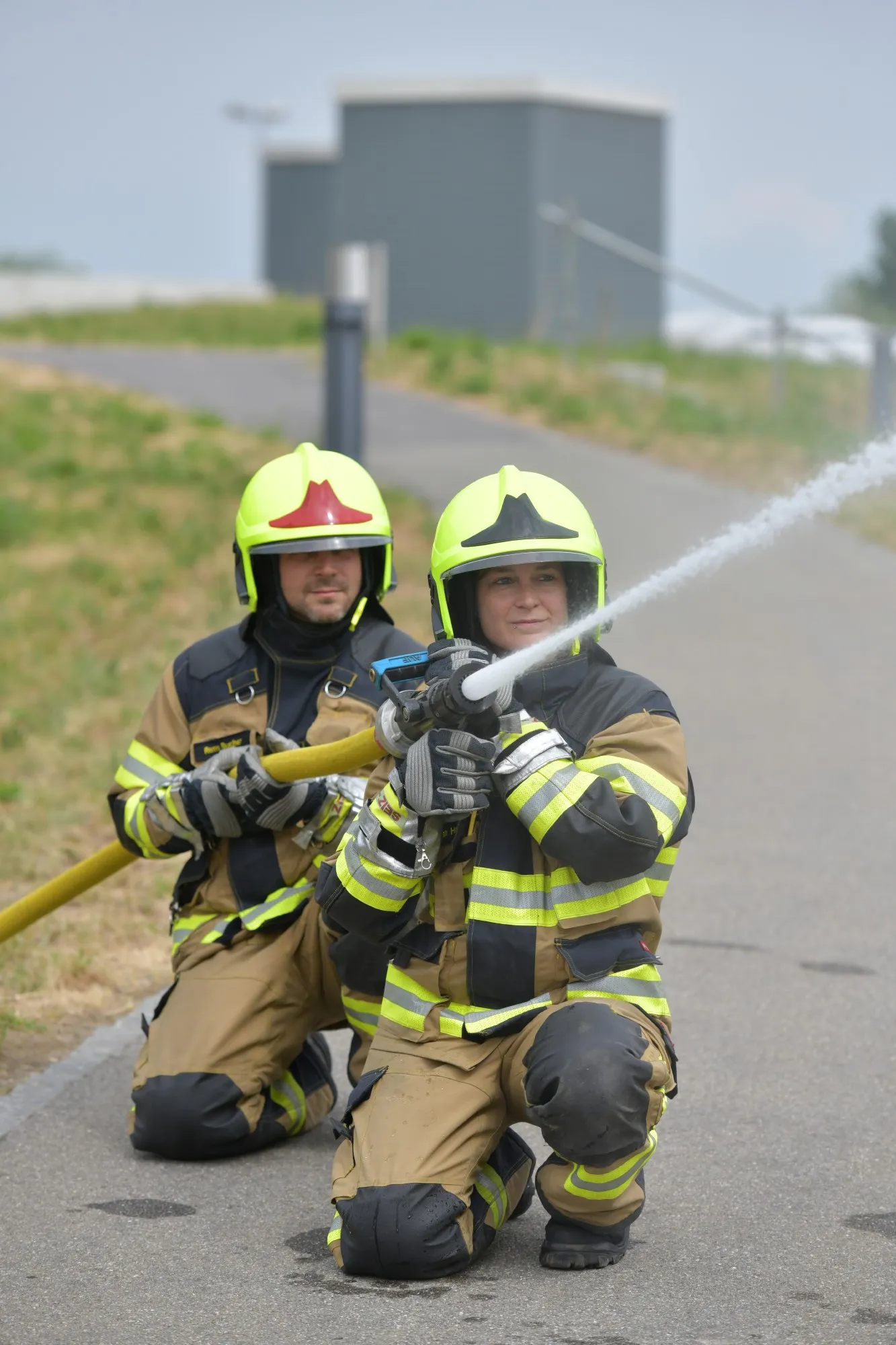 Zwei Mitarbeitende der Feuerwehr halten einen Wasserschlauch.