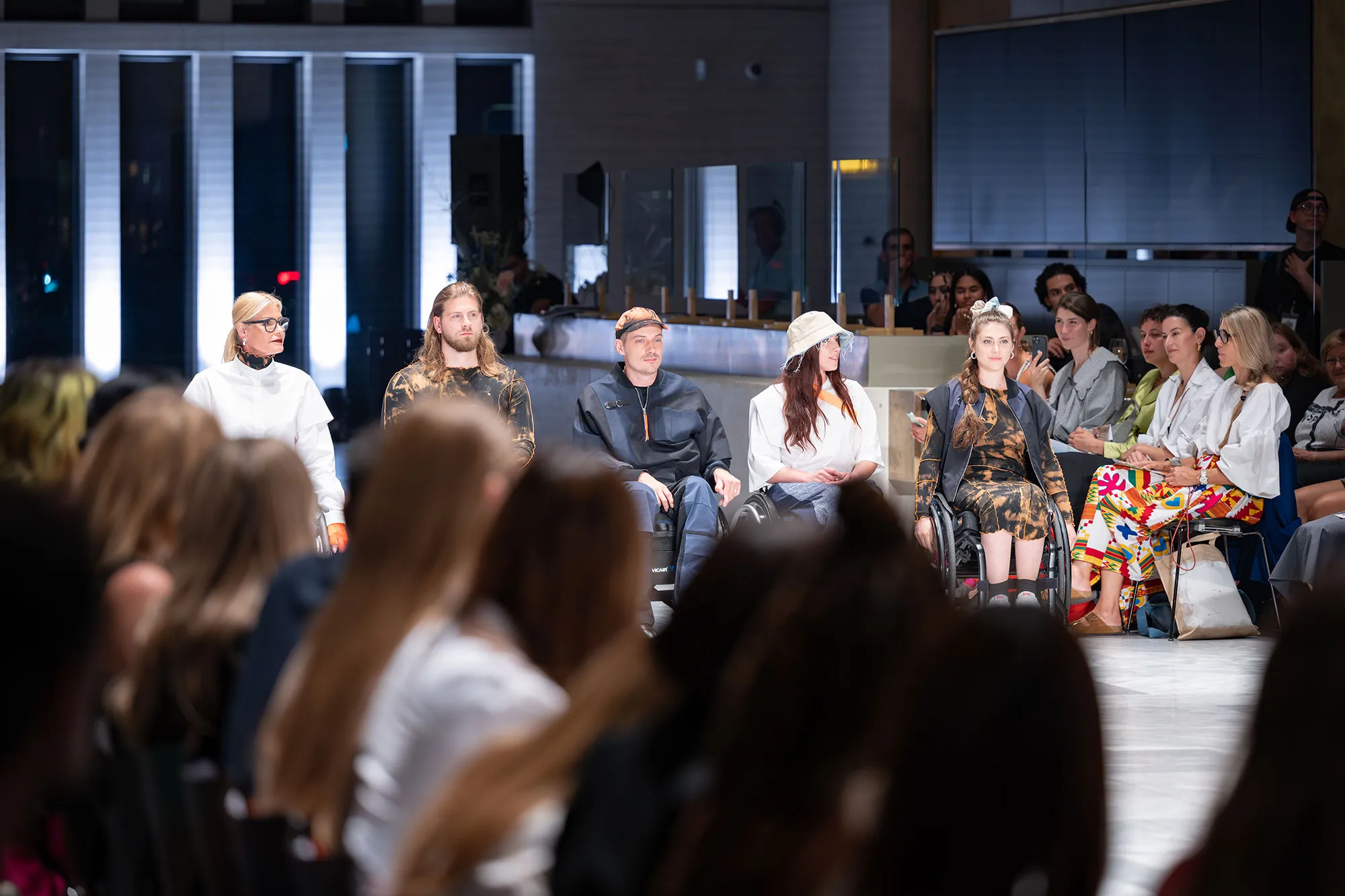 Modeschau mit rollstuhlfahrenden Models die inklusive Mode tragen.